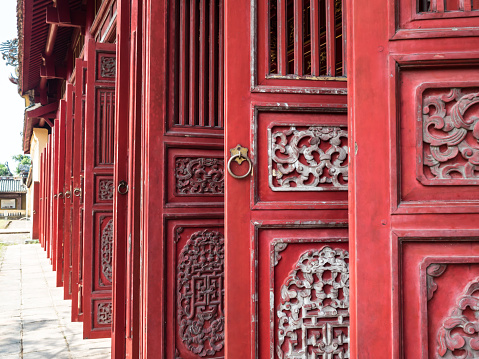 Red wooden door in the Purple Forbidden City of the Imperial City within the Citadel in Hue, Vietnam.