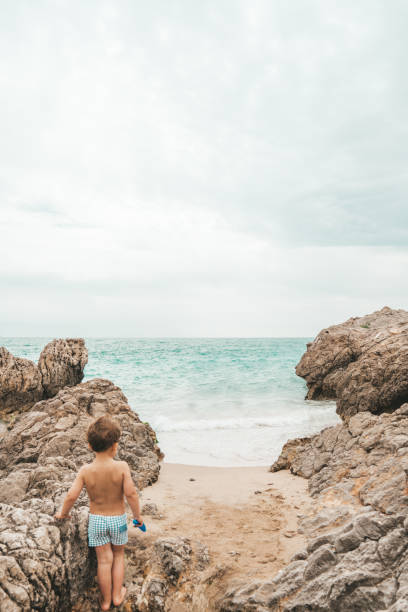 istock Boy playing in the rocks at the beach 1155407209