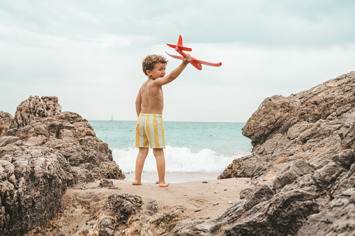 Boy playing with airplane toy at the beach
