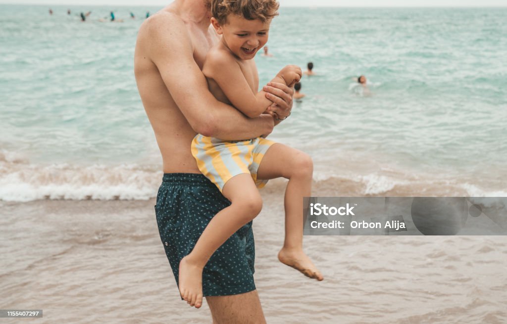 Boy playing with father at the beach Independence - Concept Stock Photo