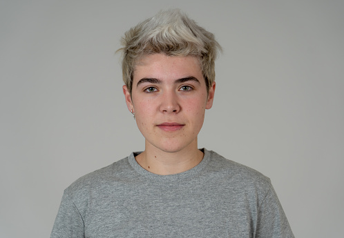 Close up portrait of young transgender teenager male with natural and neutral face and beautiful blue eyes. Isolated on neutral background. In People Diversity Human Beauty and Emotions concept.