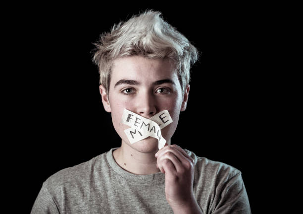 Transgender teenager with mouth sealed on tape about to break his silence about own gender identity in Breaking social taboos and freedom concept. Human rights Equality and Gender Diversity campaign. Transgender teenager with mouth sealed on tape about to break his silence about own gender identity in Breaking social taboos and freedom concept. Human rights Equality and Gender Diversity campaign. gender neutral photos stock pictures, royalty-free photos & images
