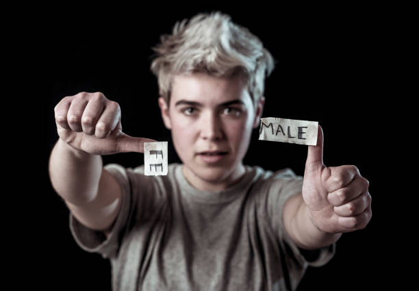 guapo adolescente transgénero desgarrando la palabra female en male en identidad de género, igualdad y derechos humanos. rompiendo el silencio sobre la identidad de género, el orgullo transgénero y el concepto de libertad. - teenage sex fotografías e imágenes de stock