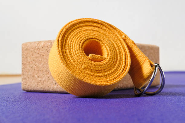 accessori per praticare yoga. mattone di sughero e cinturino giallo su tappetino viola. - purple belt foto e immagini stock