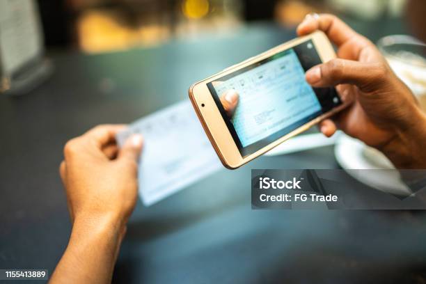 Young Woman Depositing Check By Phone In The Cafe Stock Photo - Download Image Now - Mobile Phone, Banking, Portable Information Device