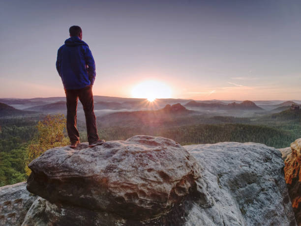 istock Man walking over rocky summit at rising Sun. Beautiful moment 1155417151