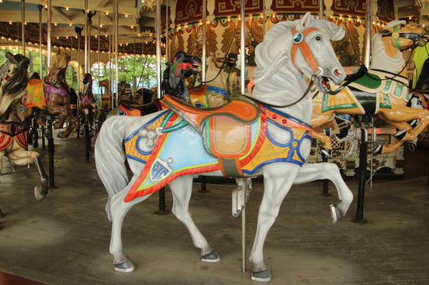 weißes karussell mit mehrfartendem sattel - carousel horses stock-fotos und bilder