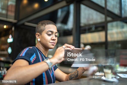istock Young woman depositing check by phone in the cafe 1155418578