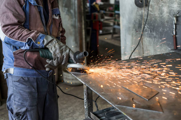 istock Workman with a mask and gloves is grinding a metal object with a grinder. He wears a protective wardrobe. 1155420451