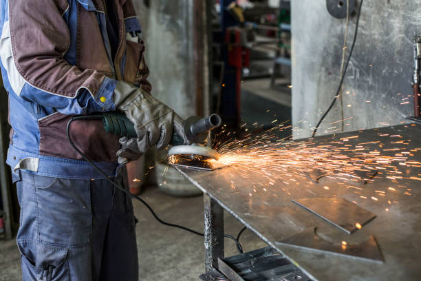 istock Workman with a mask and gloves is grinding a metal object with a grinder. He wears a protective wardrobe. 1155420620