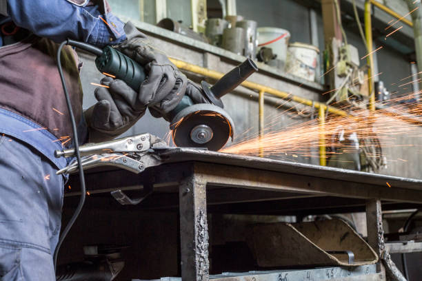 istock Workman with a mask and gloves is grinding a metal object with a grinder. He wears a protective wardrobe. 1155420767