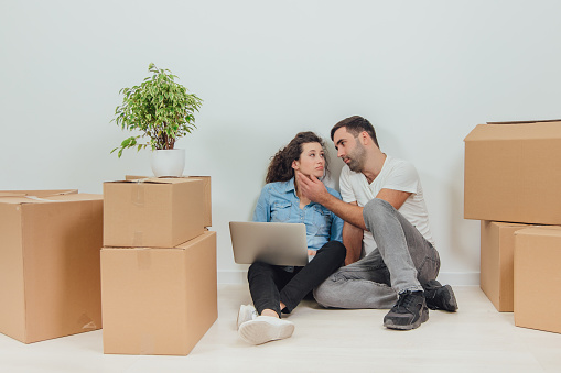 Concept of relocation. Portrait of wife and husband moving into new flat. White background. Full-length.