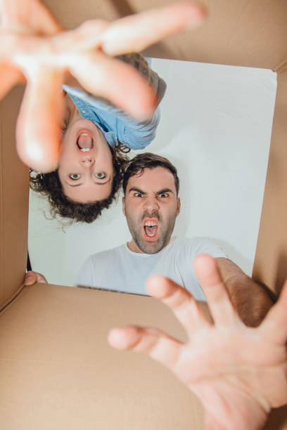 istock Curious wife and husband unpacking, reaching things from carboard box, looking inside, roaring like monsters. 1155424802