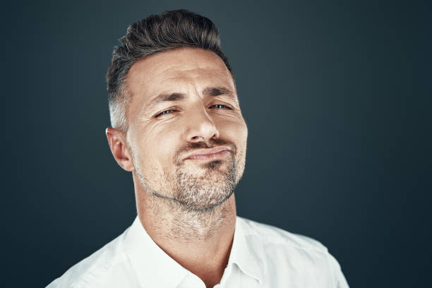 istock Too confident. Handsome young man smiling and looking at camera while standing against grey background 1155427637