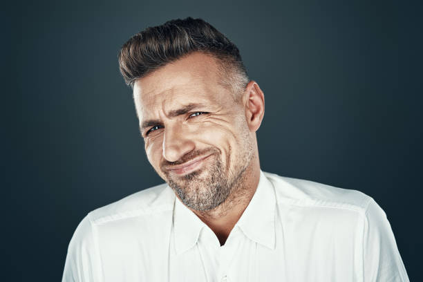 istock Confusion. Displeased young man grimacing and looking at camera while standing against grey background 1155428233
