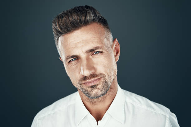 istock Perfect man. Handsome young man smiling and looking at camera while standing against grey background 1155428688