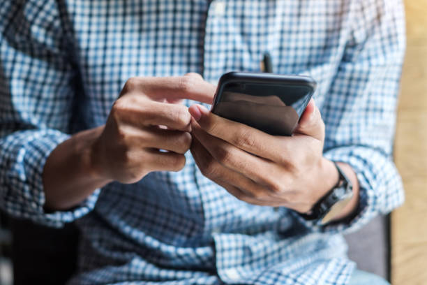 istock Young casual Businessman holding and using smartphone for sms messages, hipster man typing touchscreen cell phone in the cafe. business, lifestyle, technology and Social media network concept 1155429053