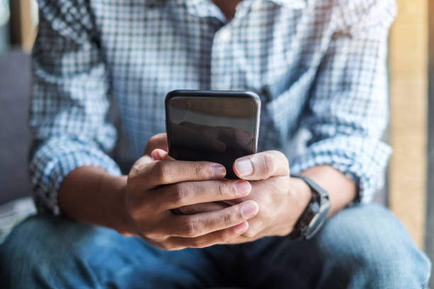 istock Young casual Businessman holding and using smartphone for sms messages, hipster man typing touchscreen cell phone in the cafe. business, lifestyle, technology and Social media network concept 1155429151