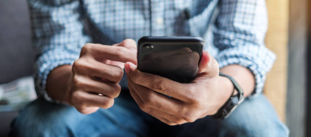 istock Young casual Businessman holding and using smartphone for sms messages, hipster man typing touchscreen cell phone in the cafe. business, lifestyle, technology and Social media network concept 1155429771