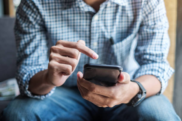 istock Young casual Businessman holding and using smartphone for sms messages, hipster man typing touchscreen cell phone in the cafe. business, lifestyle, technology and Social media network concept 1155429835