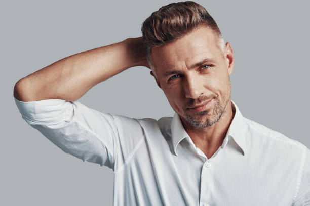 istock Real macho. Handsome young man looking at camera and smiling while standing against grey background 1155430097