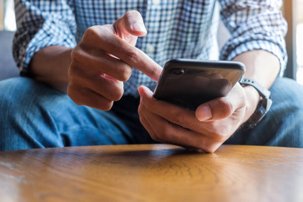 istock Young casual Businessman holding and using smartphone for sms messages, hipster man typing touchscreen cell phone in the cafe. business, lifestyle, technology and Social media network concept 1155430319