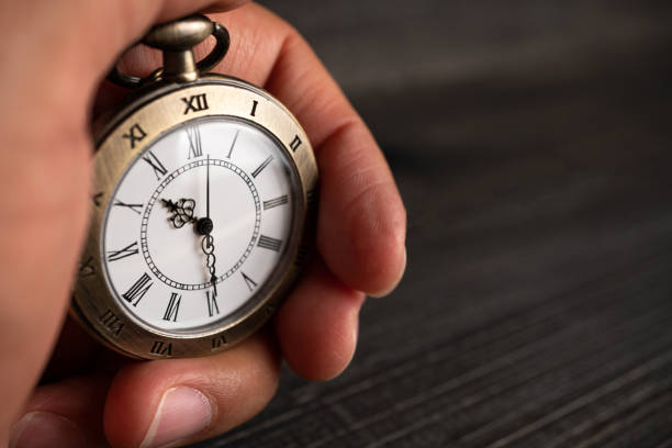 istock Men hands hold a pocket watch and a black background. 1155431557
