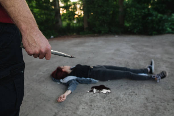 istock Insane murderer holding a knife in front of his dead victim 1155432342