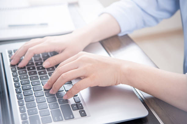 istock Business concept. Woman in blue shirt typing on computer with coffee on office table, backlighting, sun glare effect, close up, side view, copy space 1155432936