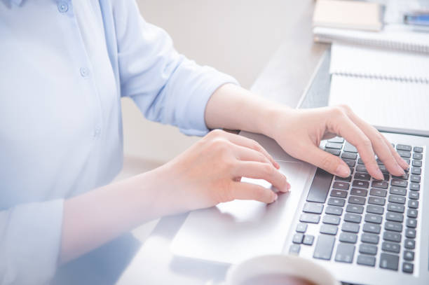 istock Business concept. Woman in blue shirt typing on computer with coffee on office table, backlighting, sun glare effect, close up, side view, copy space 1155433095