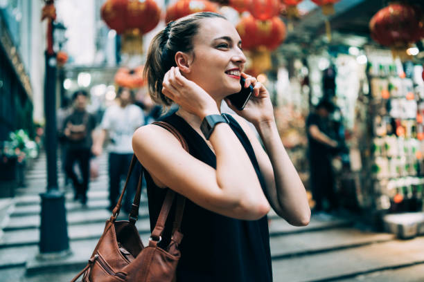 istock Blond woman talking on smart phone on street with red lanterns 1155433165