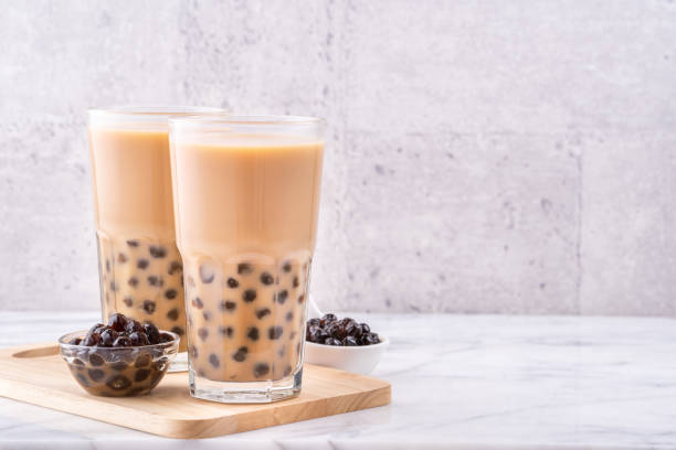 Popular Taiwan drink - Bubble milk tea with tapioca pearl ball in drinking glass on marble white table wooden tray background, close up, copy space Popular Taiwan drink - Bubble milk tea with tapioca pearl ball in drinking glass on marble white table wooden tray background, close up, copy space bubble tea photos stock pictures, royalty-free photos & images