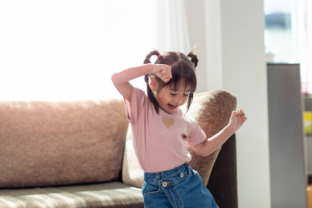 feliz niño asiático divertirse y bailar en una habitación - saltar actividad física fotografías e imágenes de stock
