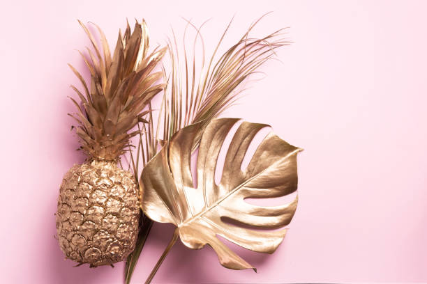 istock Creative layout. Gold pineapple and golden palm, monstera on pink background with copy space. Top view. Tropical flat lay. Exotic food concept, crazy trend. Banner 1155442329