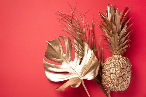 istock Creative layout. Gold pineapple and golden palm, monstera on red background with copy space. Top view. Tropical flat lay. Exotic food concept, crazy trend. Banner 1155442594