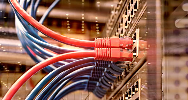 rack de serveur avec les câbles bleus et rouges de corde de correction d'internet connectés au panneau noir de correction dans la salle de serveur de données - internet network connection plug computer cable telecommunications equipment photos et images de collection