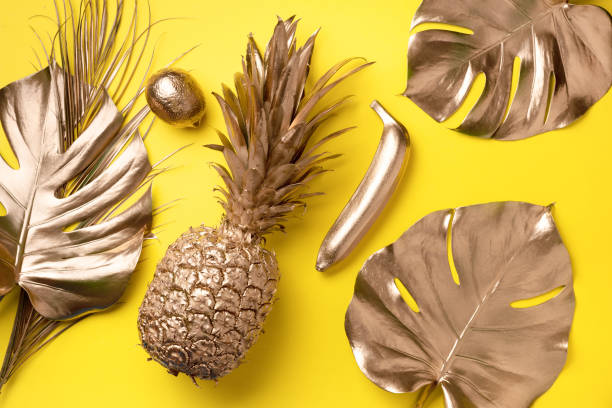 istock Creative layout. Gold pineapple and golden palm, monstera on yellow background with copy space. Top view. Tropical flat lay. Exotic food concept, crazy trend. Banner 1155443927