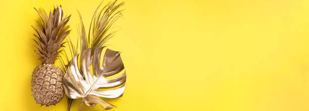 istock Creative layout. Gold pineapple and golden palm, monstera on yellow background with copy space. Top view. Tropical flat lay. Exotic food concept, crazy trend. Banner 1155443938