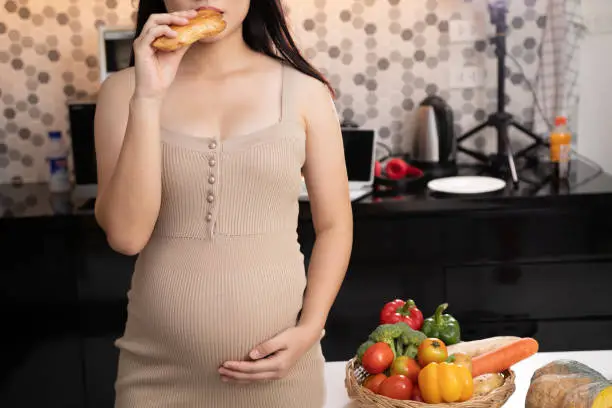 Young Mother-to-be eating harmful Pineapple Pie sitting , high fat nutrition, junk food.