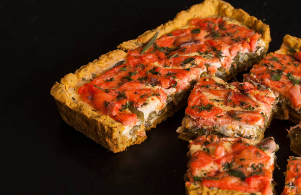 istock Rectangular quiche with salmon, spinach and cream on a black wooden table. French cuisine. 1155449802