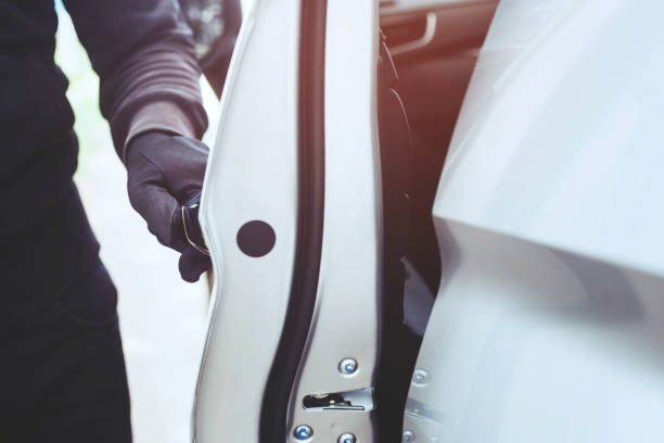 istock Close up hand pulling the handle of a car thief wearing black clothes and glove stealing automobile trying door handle to see if vehicle is unlocked trying to break into. car theft concept. 1155450262