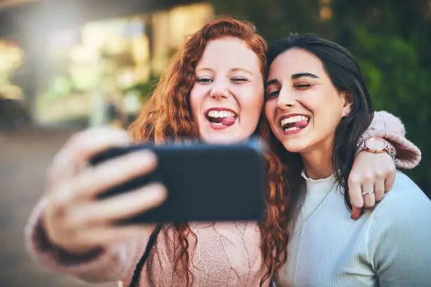 Cropped shot of two friends taking a selfie while out in the city