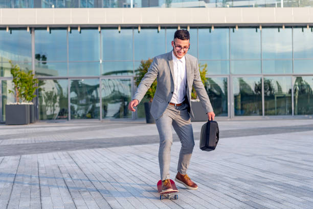 istock Stylish manager riding a skateboard in city 1155454014