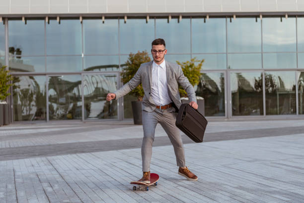 istock Stylish manager riding a skateboard in city 1155454146