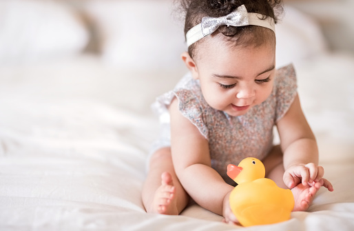 Shot of a beautiful little girl sitting playing with a toy duck on bed