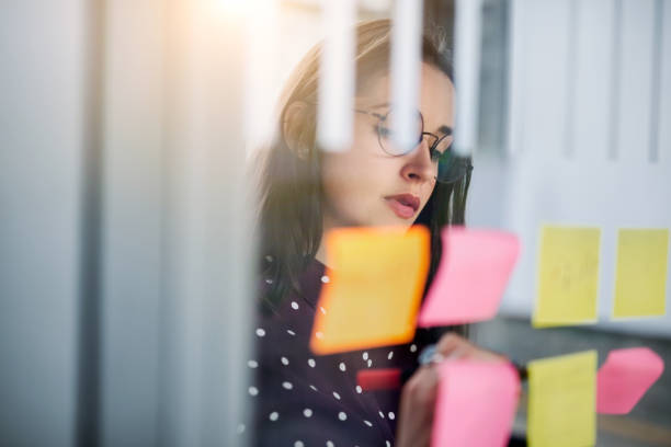 istock Woman writing on sticky note in brainstorming meeting 1155461071
