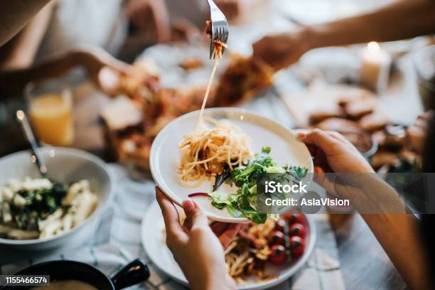 Group Of Joyful Young Asian Man And Woman Having Fun Passing And Sharing Food Across Table During Party Stock Photo - Download Image Now
