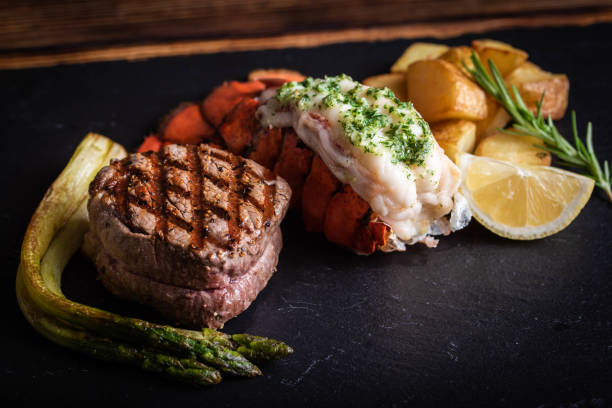 surf y césped sobre placa de piedra negra - surf and turf prepared shrimp steak grilled fotografías e imágenes de stock