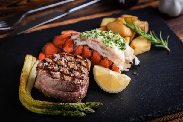 surf y césped sobre placa de piedra negra - surf and turf prepared shrimp steak grilled fotografías e imágenes de stock