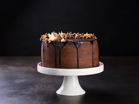Banner chocolate and coffee cake. Tasty chocolate drip cake with melting chocolate on a dark background. Space for text.